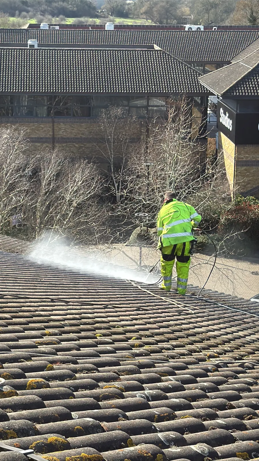 Commercial roof pressure washing in progress on a large tiled roof