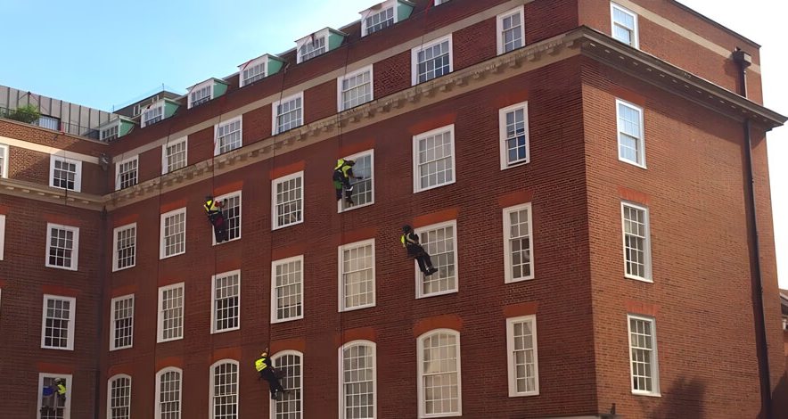 Rope access contractors working on a commercial brick building