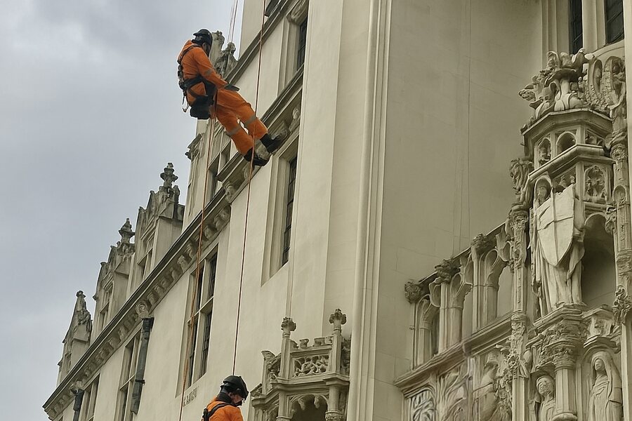 Rope-access technician closely inspecting an ornate building façade