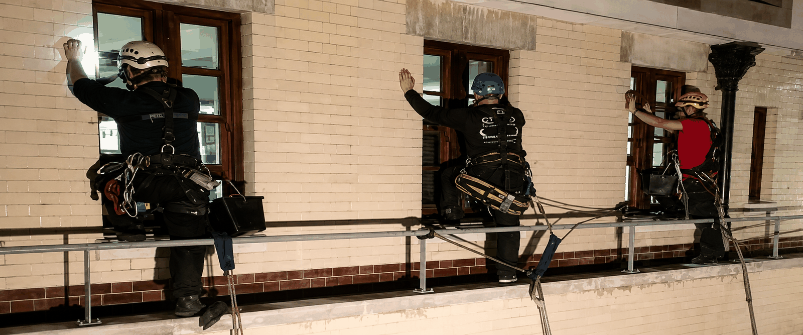 Three CCS rope access technicians positioned at sash windows during the HM Treasury project in London